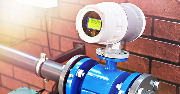 Picture of a Blue and white Smart Water Meter against a brick wall. 